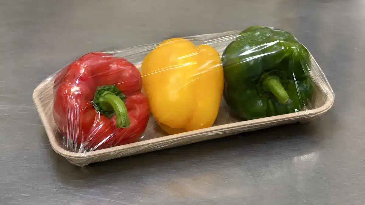 Mixed bell peppers held in a shallow tray under clear shrink overwrap